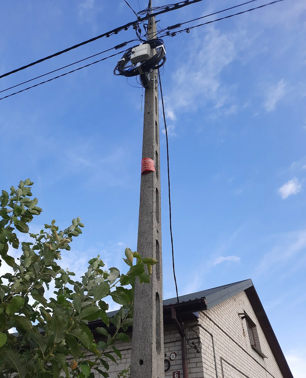 Aerial ADSS fiber cable and a pole-mounted fiber enclosure with a coiled service loop on a rural utility pole