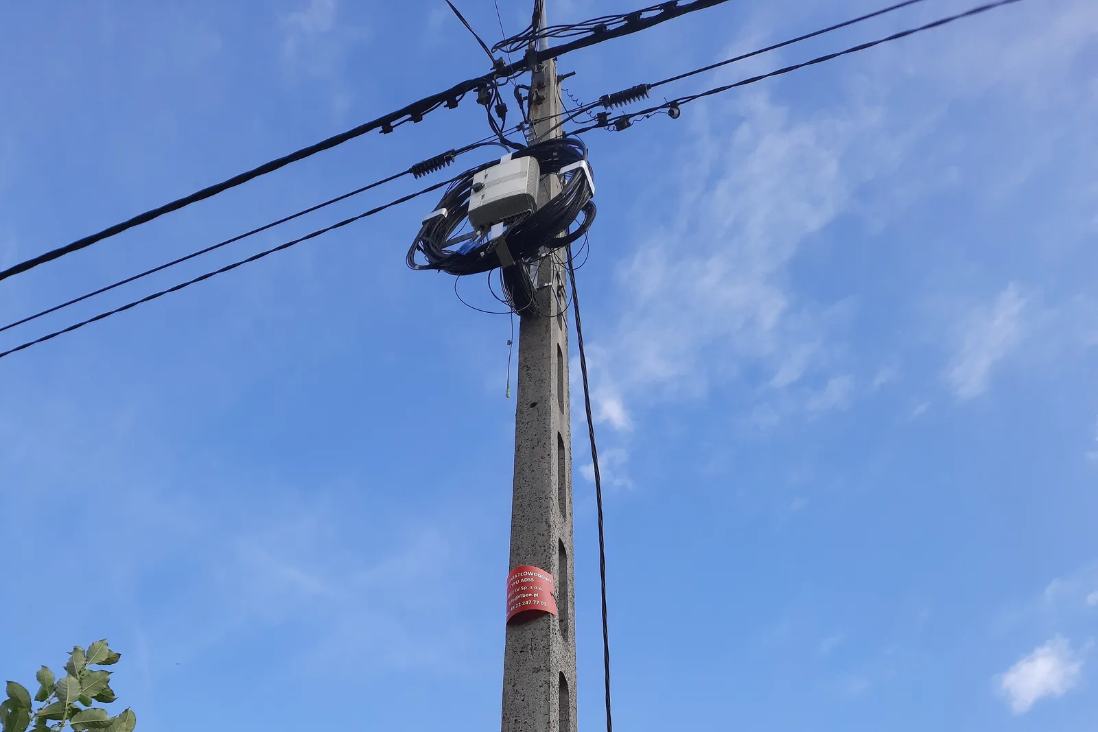 Aerial ADSS fibre optic cable spans on a concrete utility pole, with an FTTH access box and coiled service loop — outside plant construction that falls outside the scope of the EU Construction Products Regulation