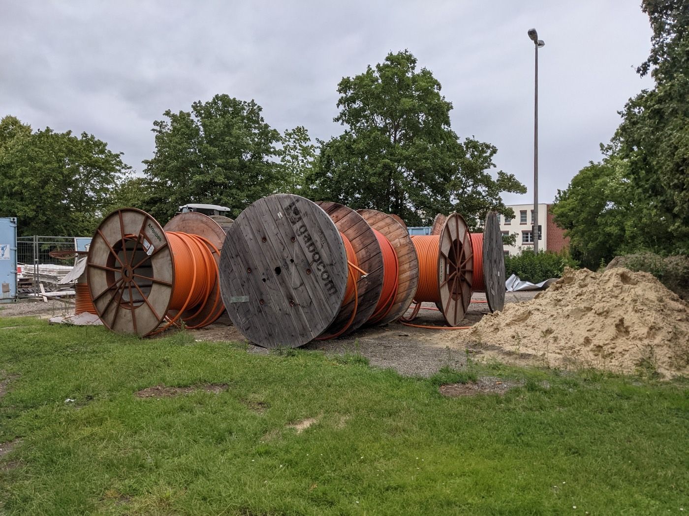 Wooden cable drums and orange conduit staged at a fiber-optic construction site