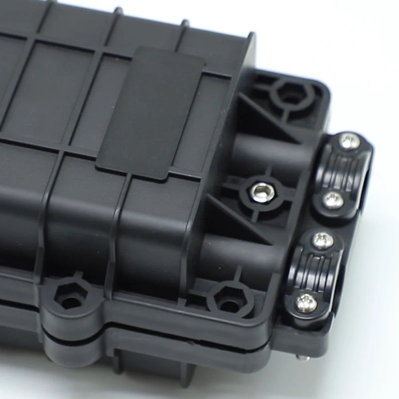 Close-up of the mechanical clamp and cable entry ports on a fiber optic splice closure, showing the screw-down hardware that creates a re-enterable seal