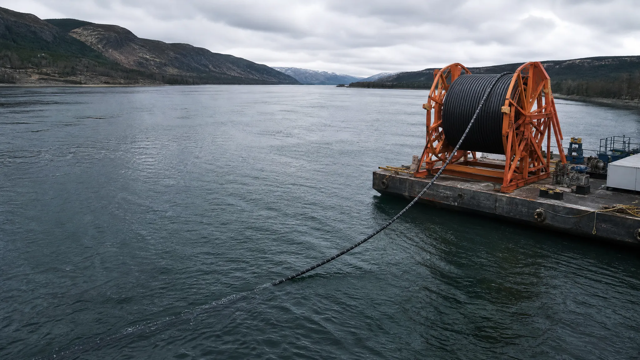 Steel wire armored fiber optic cable being laid across a river crossing on a barge-mounted reel